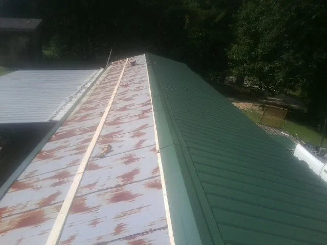 Old rusted panels beside newly installed green metal roofing — Wind Damage Roof Repair by Roofing Brothers in Seymour